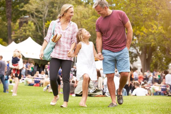 A family walking hand in hand across the grass at an outdoor fair
